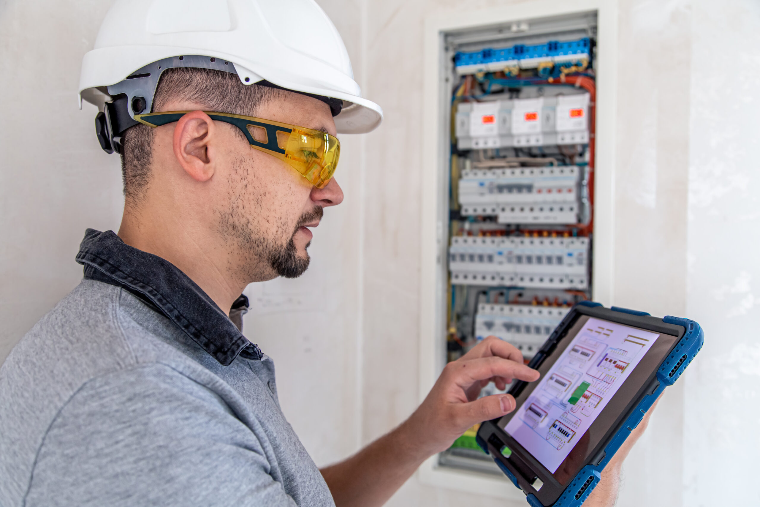 Electrical technician looking focused while working in a switchboard with fuses. Electrical technician looking focused while working in a switchboard with fuses.